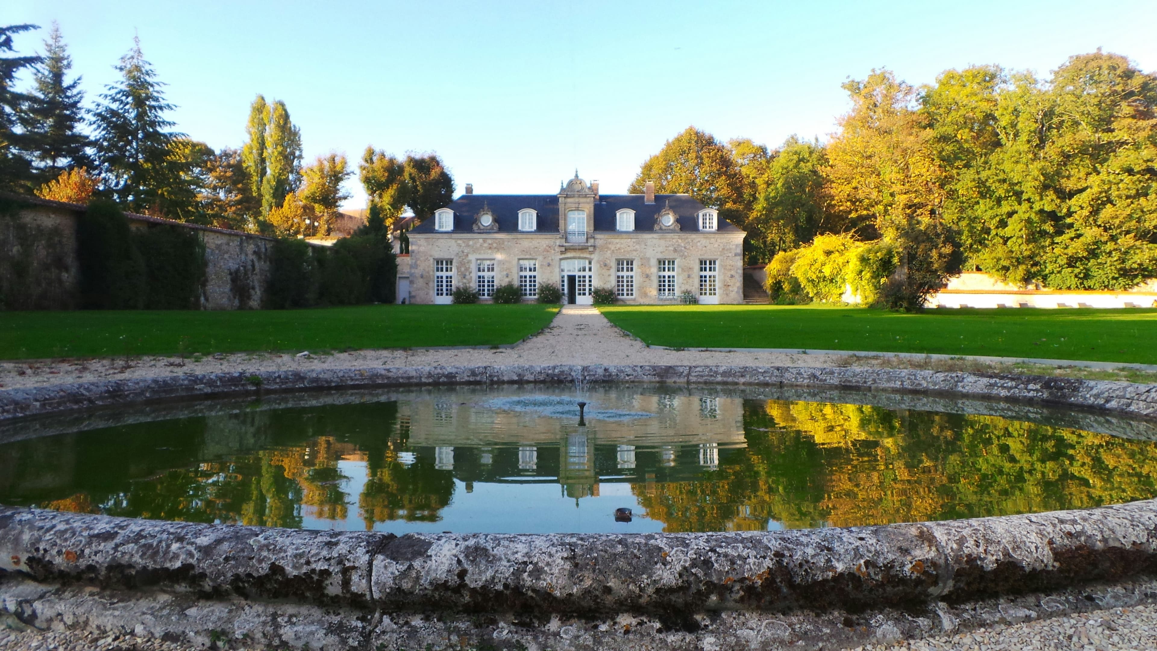 Étang devant un bâtiment entouré d'arbres